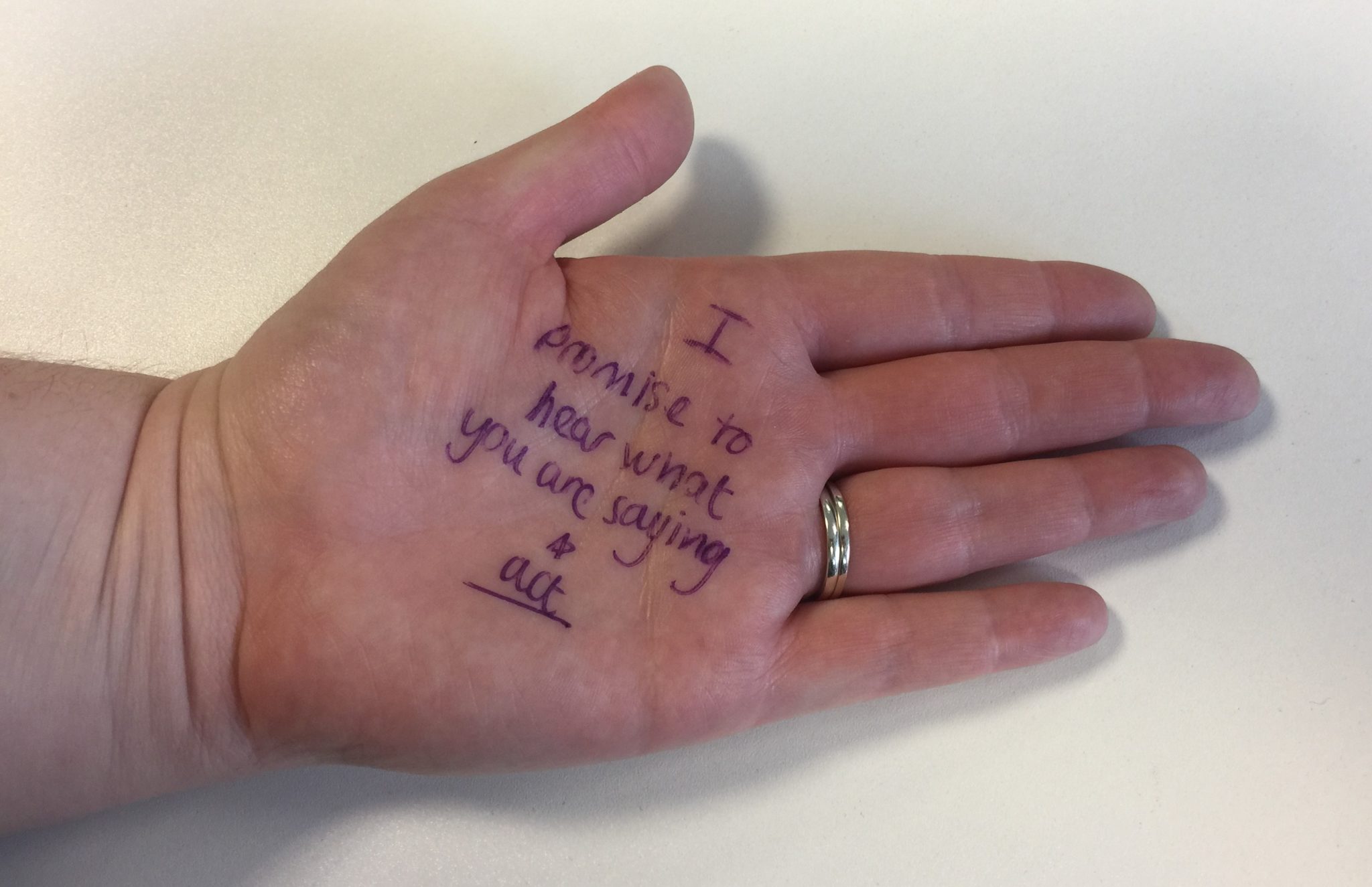 hand with the words "I promise to hear what you are saying and act"