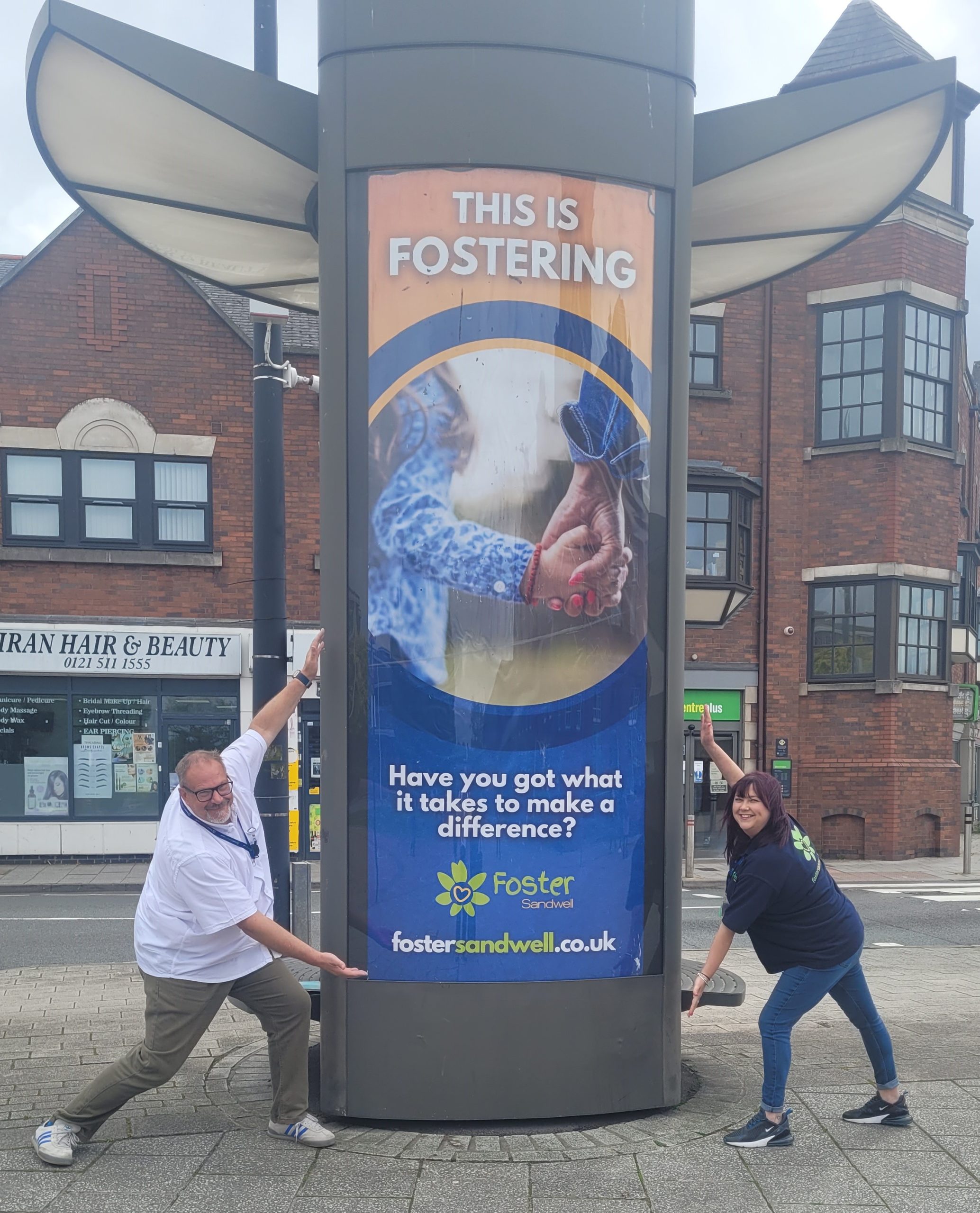 Dave and Sophie standing beside our latest fostering poster in Oldbury town centre